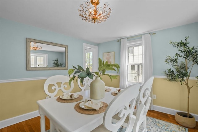 dining room featuring a healthy amount of sunlight, baseboards, an inviting chandelier, and wood finished floors