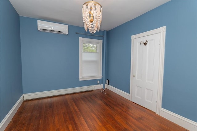 spare room with baseboards, a wall mounted AC, a chandelier, and wood finished floors