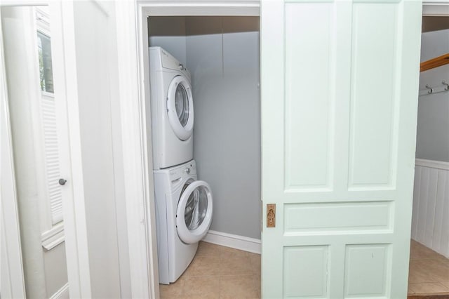 washroom with laundry area, stacked washer and dryer, and light tile patterned floors