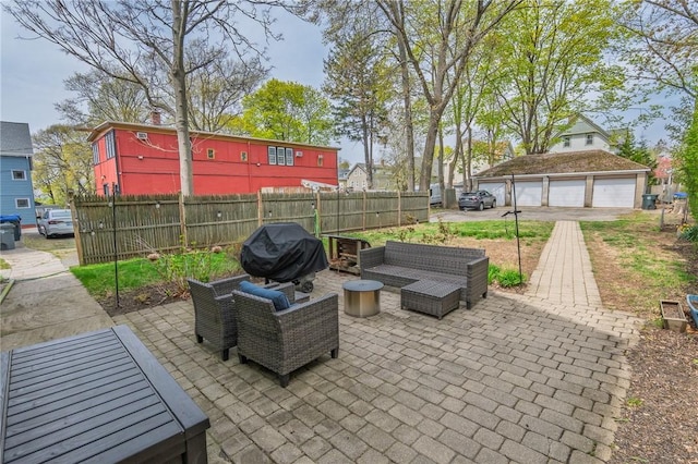 view of patio with fence, a detached garage, and a grill