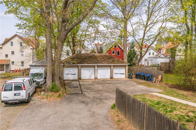 exterior space featuring an outdoor structure, a garage, fence, and a residential view