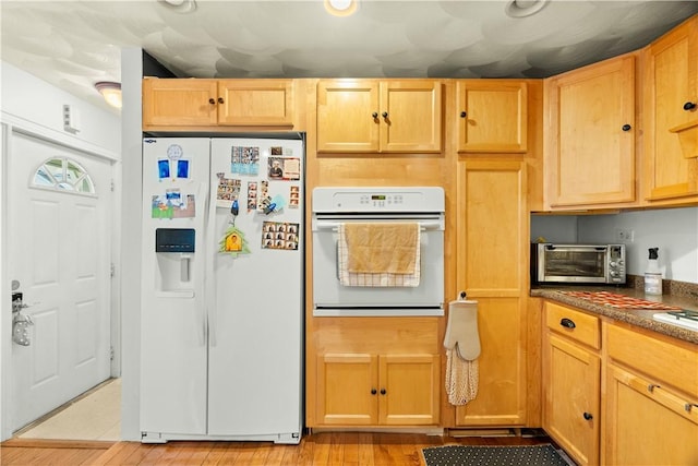 kitchen featuring a toaster, dark countertops, light wood-style floors, and white appliances