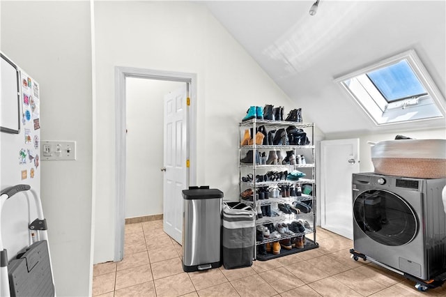 laundry area with a skylight, laundry area, light tile patterned flooring, and washer / clothes dryer