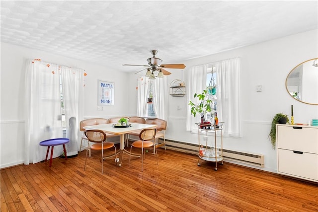 dining space featuring ceiling fan, baseboard heating, and light wood finished floors