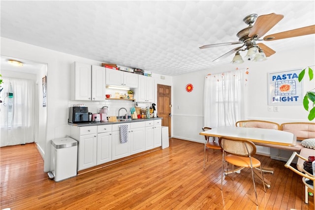 kitchen featuring light wood-style floors, white cabinetry, a healthy amount of sunlight, and tasteful backsplash