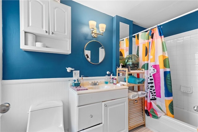 full bathroom featuring vanity, a wainscoted wall, toilet, and shower / tub combo