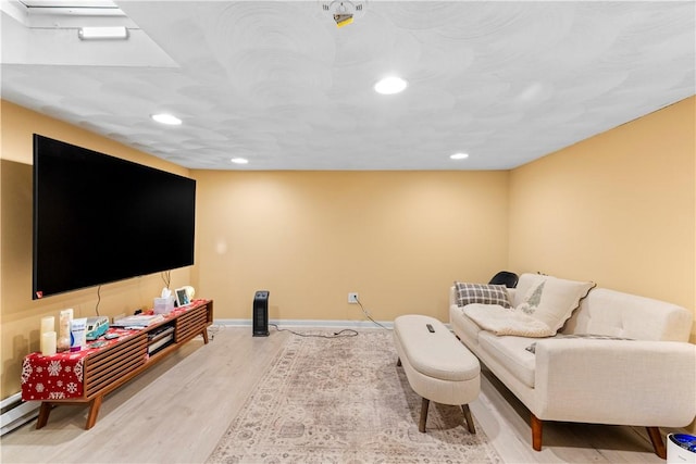 living area with baseboards, a baseboard radiator, recessed lighting, and wood finished floors