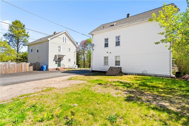 back of house with a yard, fence, and a chimney