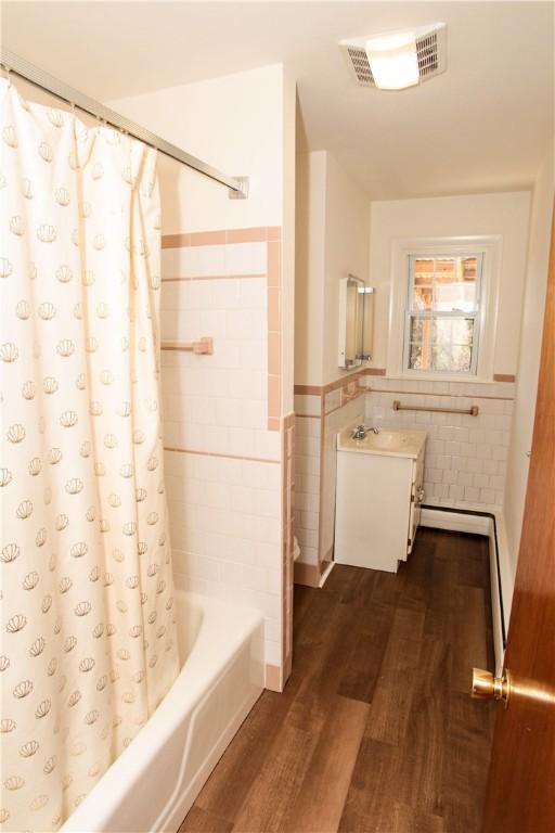 7 Smithfield Dr, Middletown, RI 02842 - bathroom with wainscoting, shower / bath combo with shower curtain, tile walls, wood finished floors, and visible vents