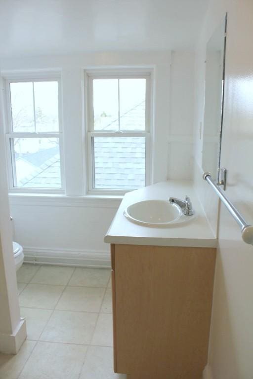 bathroom with vanity, toilet, tile patterned floors, and a wealth of natural light