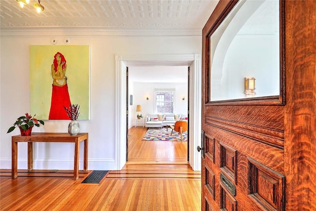 hallway featuring baseboards, crown molding, wood finished floors, and visible vents