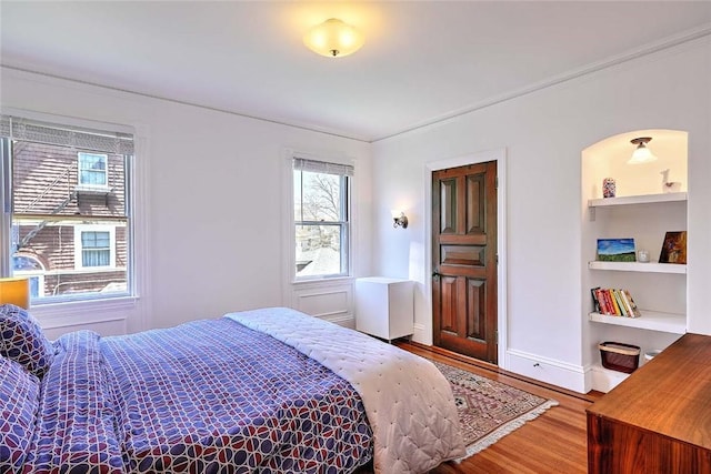 bedroom with baseboards, ornamental molding, and wood finished floors