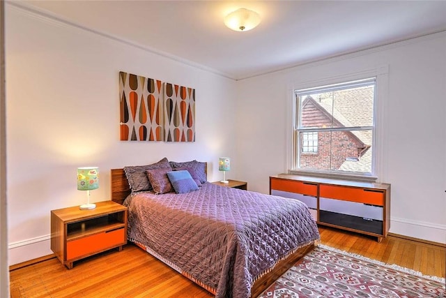 bedroom featuring crown molding, baseboards, and wood finished floors