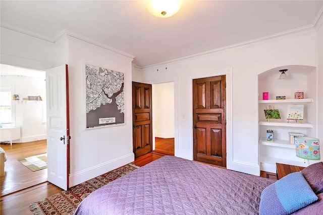 bedroom featuring crown molding, baseboards, and wood finished floors