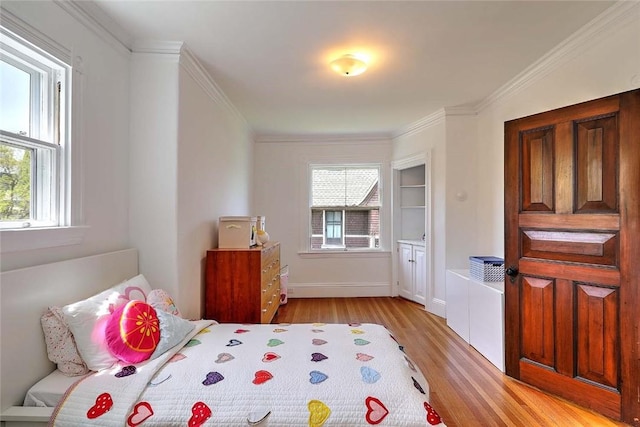 bedroom featuring baseboards, ornamental molding, light wood-style flooring, and multiple windows