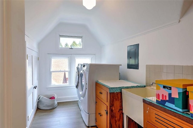 laundry area with a sink, electric panel, washing machine and dryer, and wood finished floors