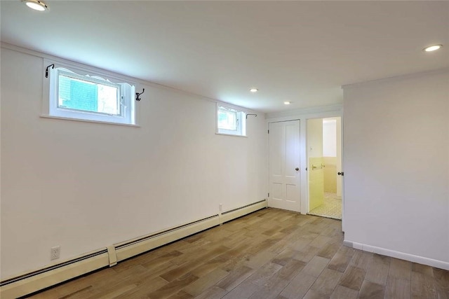 basement with baseboards, light wood-type flooring, a baseboard heating unit, and recessed lighting