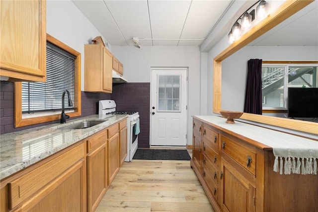 94 Cowesett Ave Unit 1, West Warwick, RI 02893 - kitchen with white gas stove, backsplash, a sink, under cabinet range hood, and light wood-style flooring