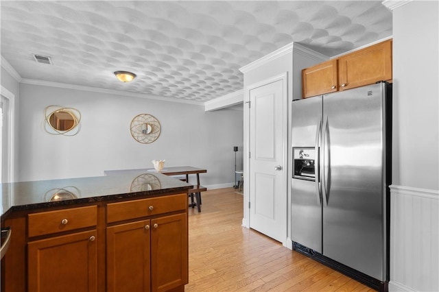 kitchen featuring brown cabinets, visible vents, stainless steel fridge, and light wood-type flooring