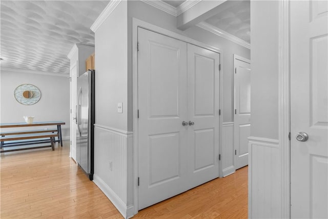 hallway with crown molding, wainscoting, and light wood finished floors