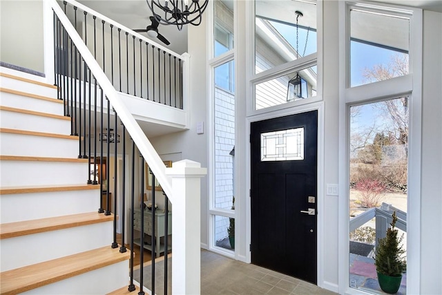 foyer featuring stairs, a healthy amount of sunlight, and a towering ceiling