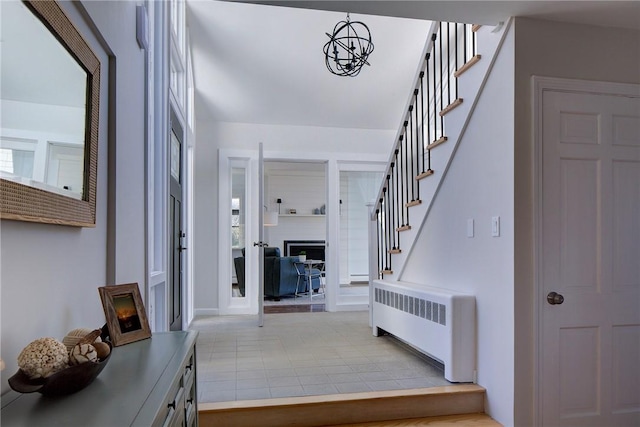 entrance foyer featuring radiator, light tile patterned floors, and stairway