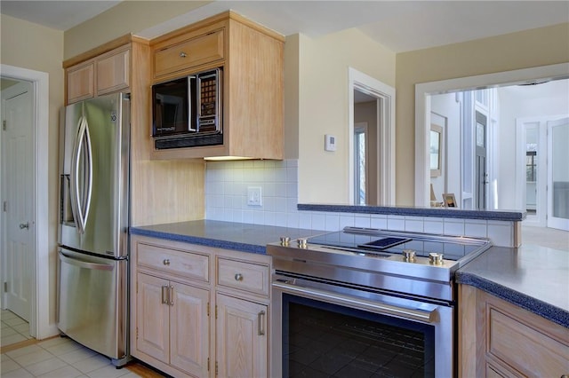kitchen with backsplash, light brown cabinetry, dark countertops, and stainless steel appliances