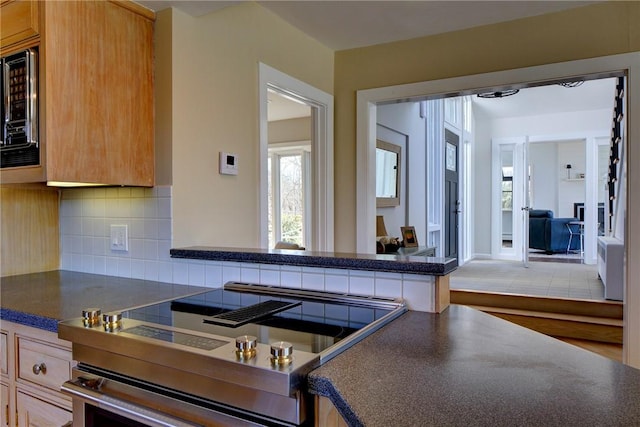 kitchen featuring decorative backsplash, dark countertops, and stove