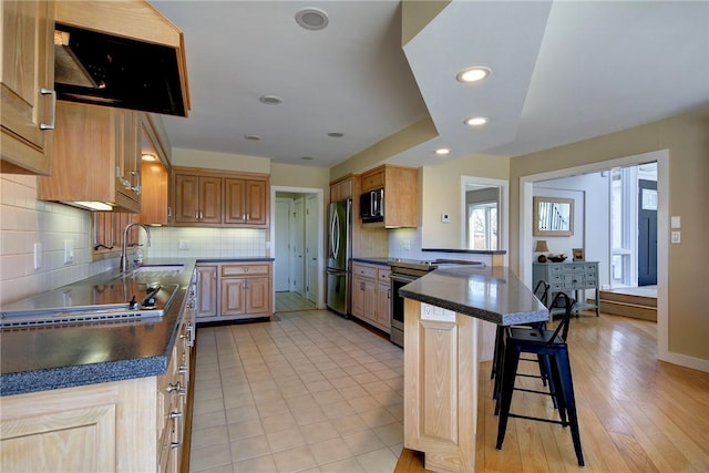 kitchen featuring appliances with stainless steel finishes, a breakfast bar area, a peninsula, recessed lighting, and backsplash