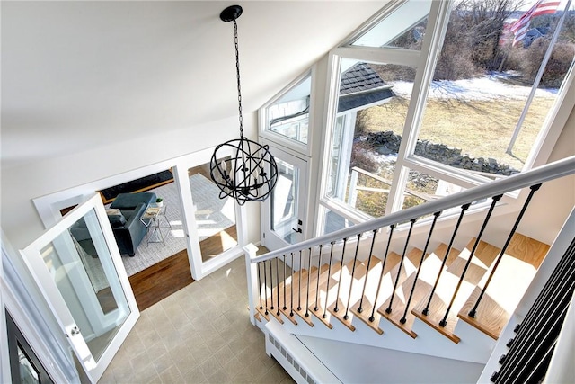 stairway with lofted ceiling, tile patterned floors, and a chandelier