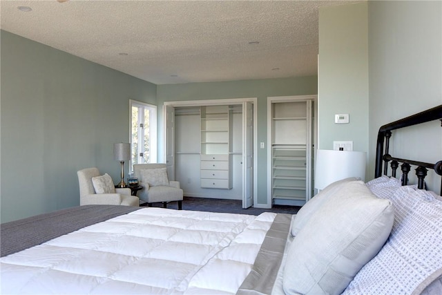 carpeted bedroom featuring a textured ceiling and multiple closets