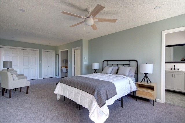 bedroom featuring a sink, a textured ceiling, carpet, and two closets