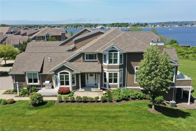 back of property with a shingled roof, a chimney, and a yard