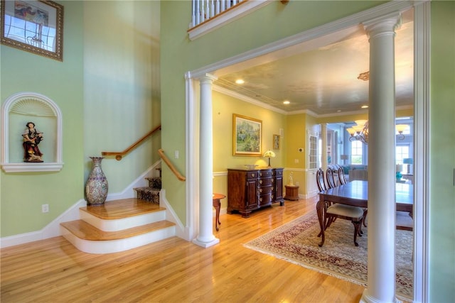 interior space with crown molding, wood finished floors, baseboards, stairway, and ornate columns