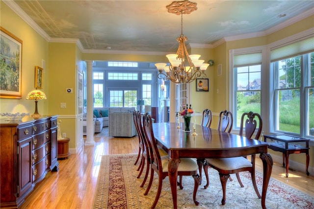 dining room with a healthy amount of sunlight, ornate columns, and light wood-style flooring