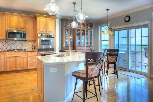 87 Waters Edge, Tiverton, RI 02878 - kitchen with light wood-style floors, a kitchen bar, light stone counters, a sink, and appliances with stainless steel finishes