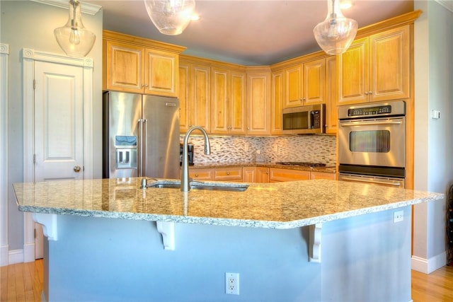 kitchen featuring decorative backsplash, a breakfast bar area, appliances with stainless steel finishes, a sink, and light stone counters