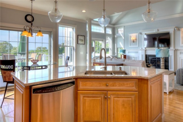 kitchen featuring stainless steel dishwasher, a sink, light stone counters, open floor plan, and light wood-style floors