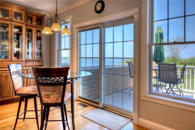 interior space featuring crown molding, baseboards, light wood finished floors, and visible vents