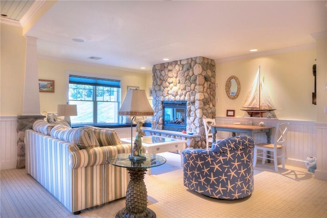 living room featuring crown molding, a stone fireplace, and a wainscoted wall