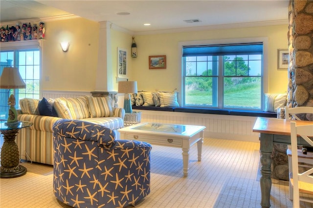 living area featuring crown molding, visible vents, a wealth of natural light, and a wainscoted wall