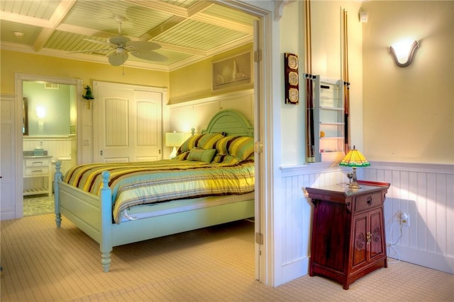 carpeted bedroom featuring connected bathroom and wainscoting