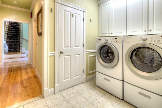 laundry area with independent washer and dryer, crown molding, cabinet space, baseboards, and light tile patterned floors