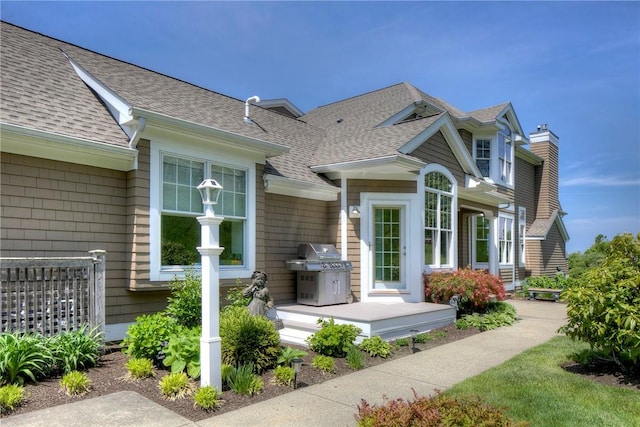 exterior space featuring a shingled roof and a chimney