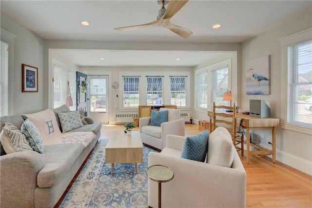 living area with a ceiling fan, light wood-type flooring, baseboards, radiator heating unit, and recessed lighting