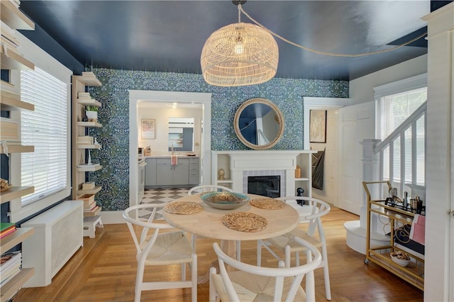 dining space featuring a glass covered fireplace, wood finished floors, and wallpapered walls