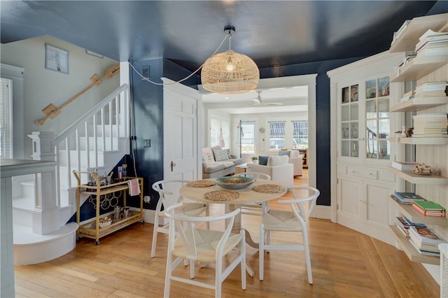 dining area featuring stairs, a ceiling fan, and light wood-type flooring