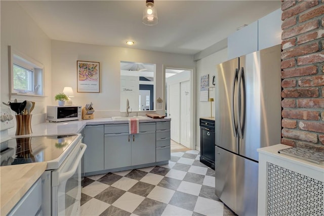 kitchen featuring a sink, light countertops, gray cabinetry, light floors, and white appliances