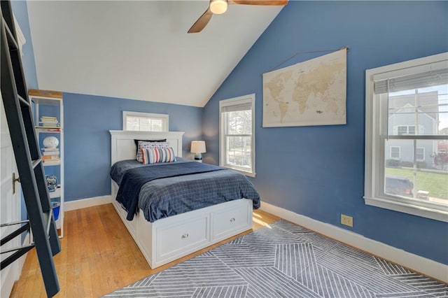 bedroom with baseboards, light wood finished floors, ceiling fan, and vaulted ceiling
