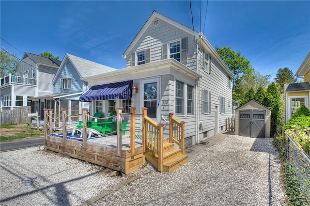 view of front of house with a deck, fence, an outbuilding, and a shed